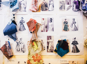 Image of a costume designer's bulletin board with sketches and fabric swatches pinned to it.